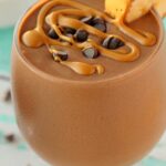Chocolate peanut butter smoothie in a glass with a straw.