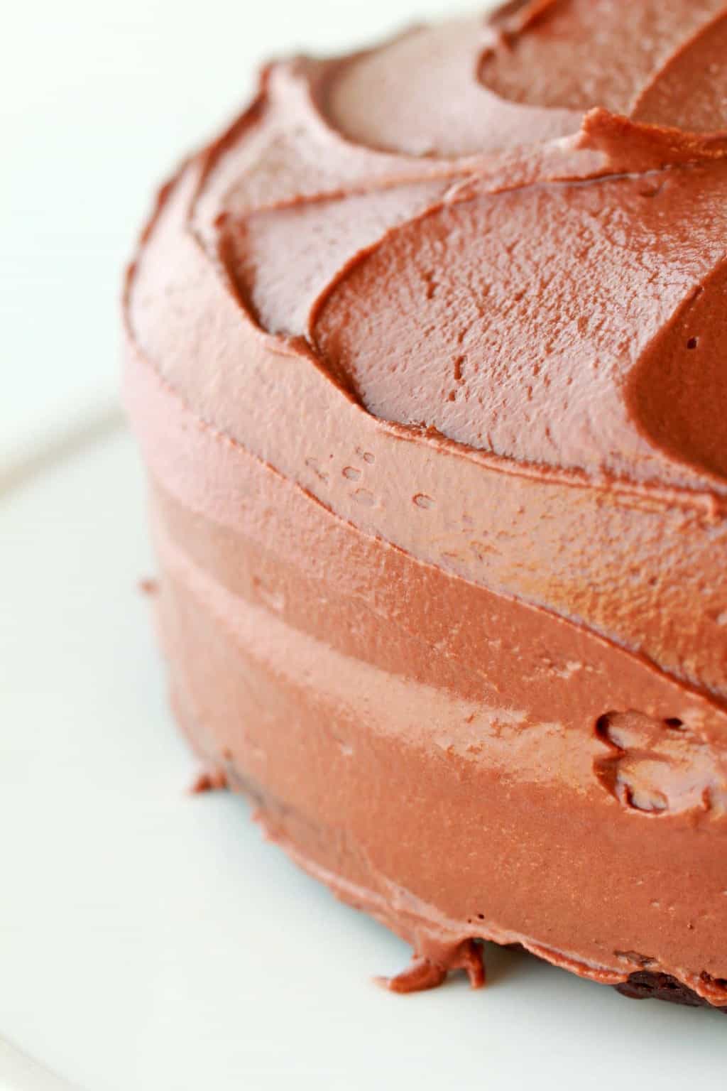 Frosted chocolate cake on a white cake stand. 