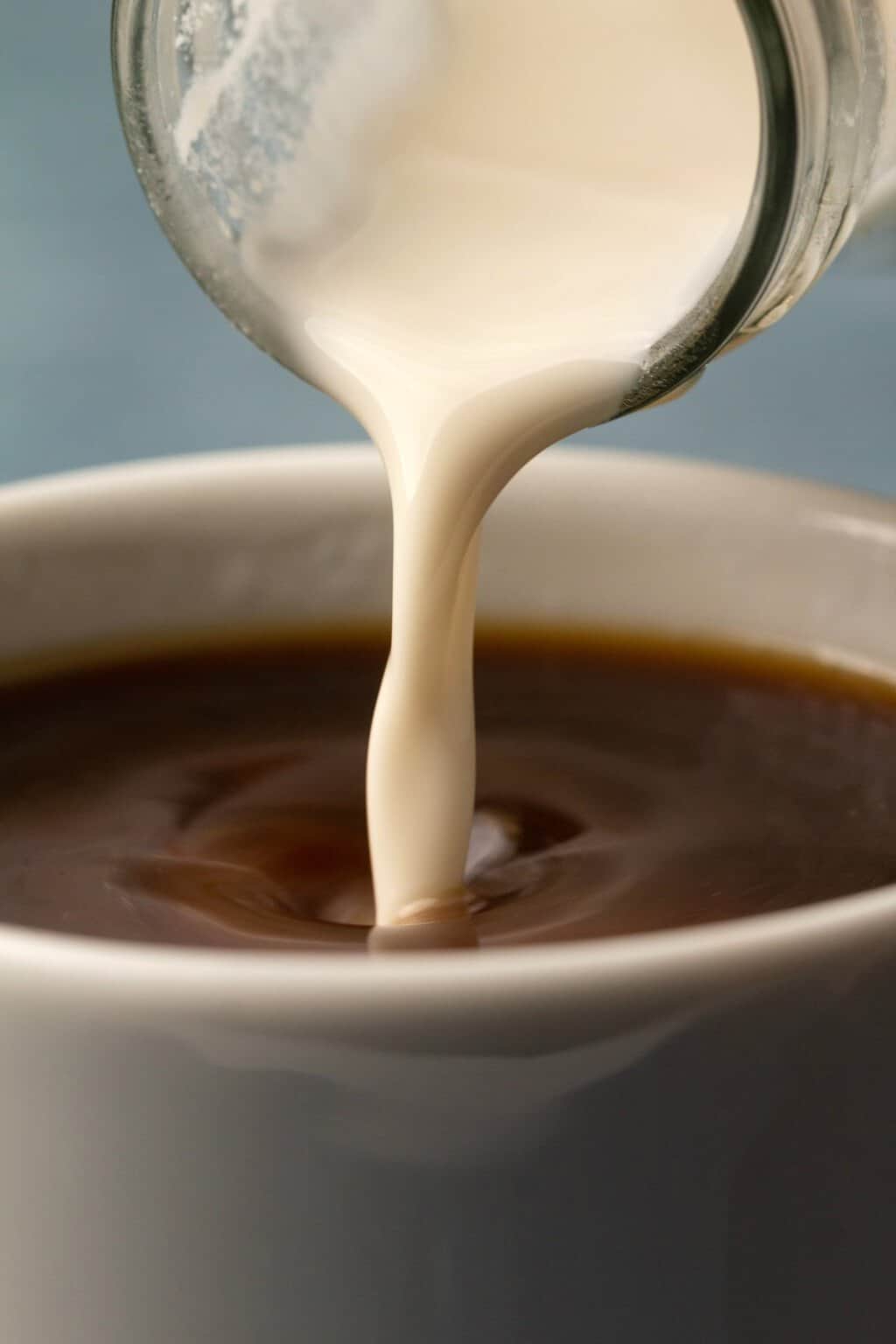 Cashew milk pouring into coffee. 