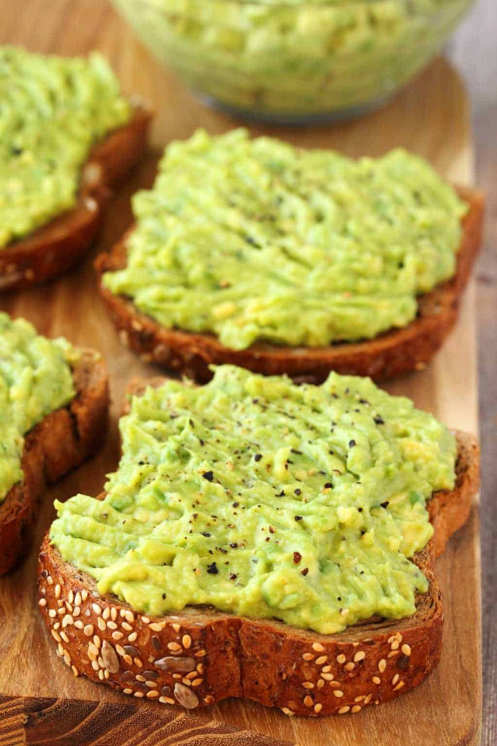 Slices of avocado toast on a wooden board.