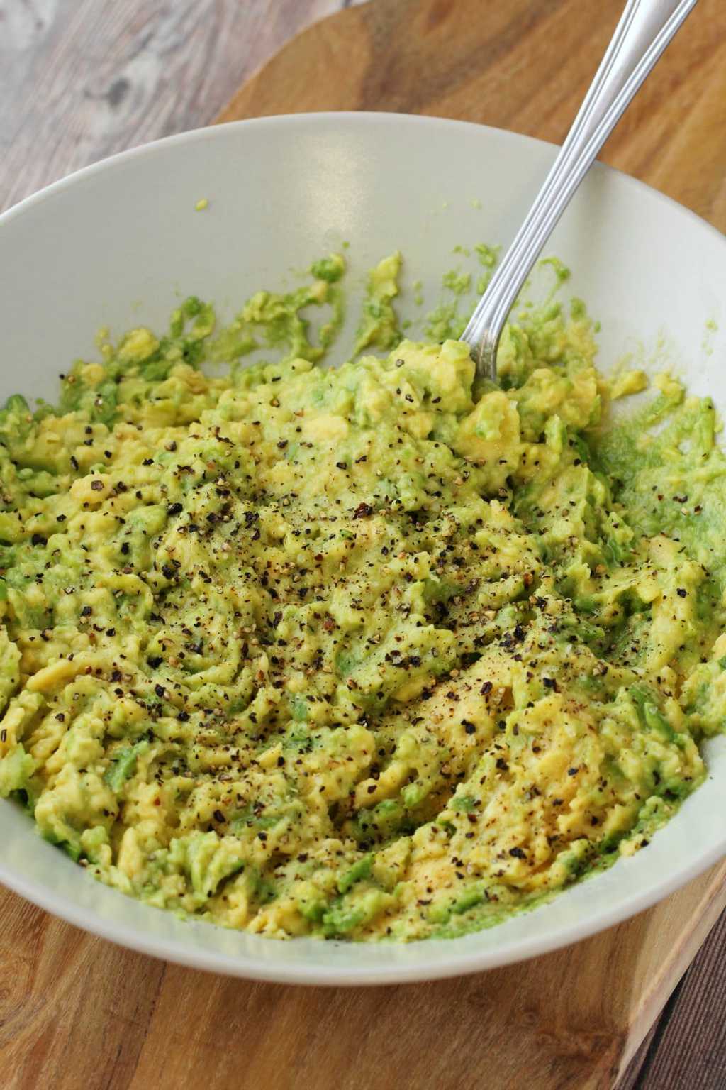 A bowl of mashed avocado topped with black pepper. 