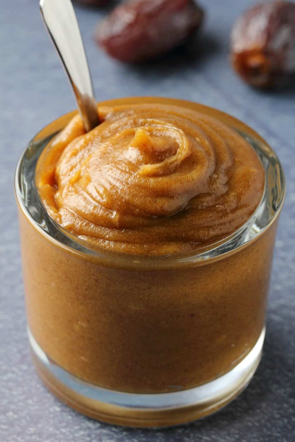 Date caramel in a glass jar with a spoon. 