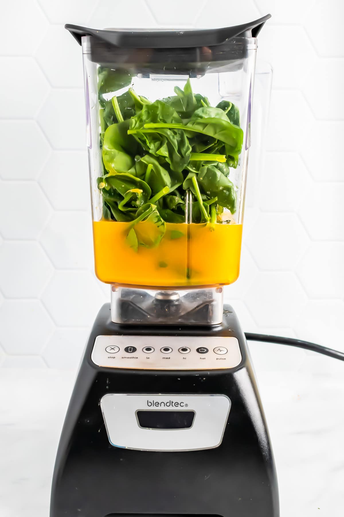 Orange juice and baby spinach in a blender jug. 
