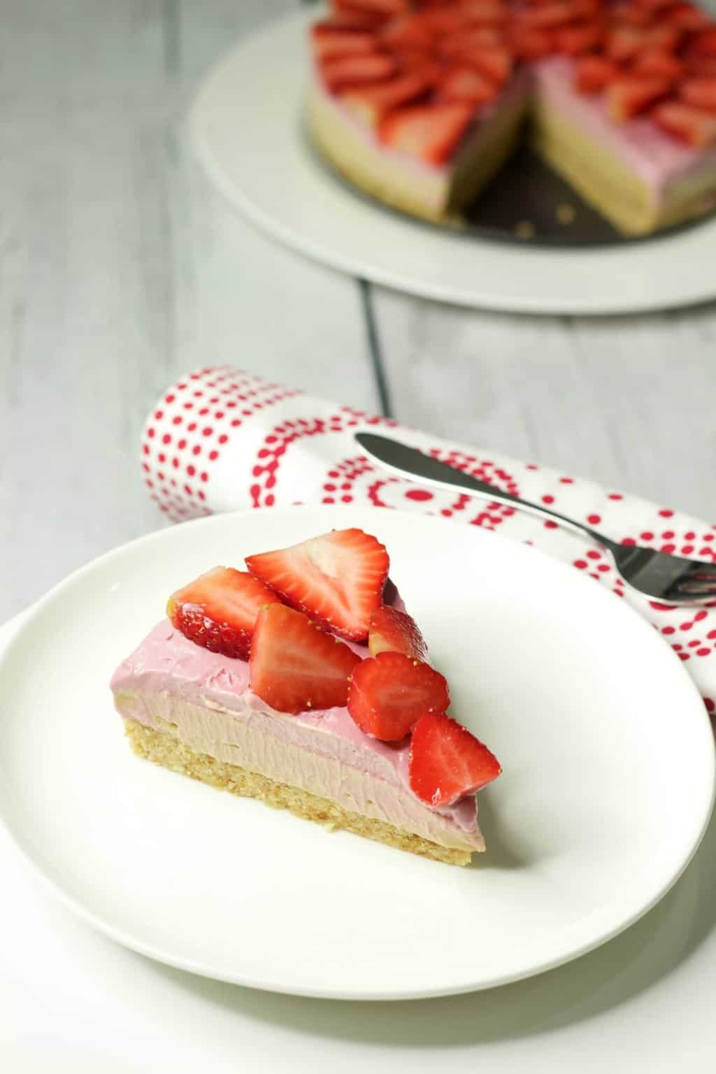 Slice of raw strawberry cheesecake on a white plate. 