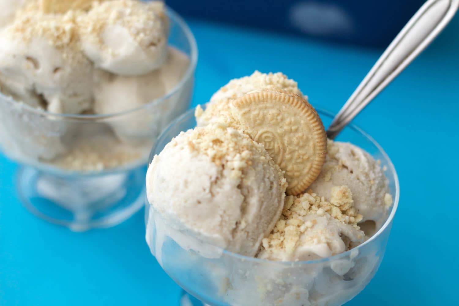 Vegan vanilla ice cream topped with golden oreo sprinkles in glass bowls. 