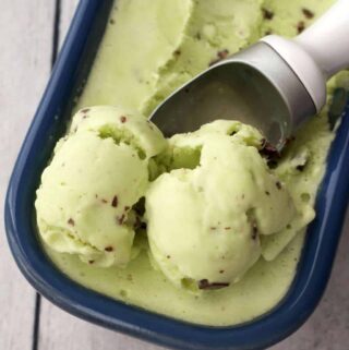 Mint chocolate chip ice cream in a blue loaf pan with an ice cream scoop