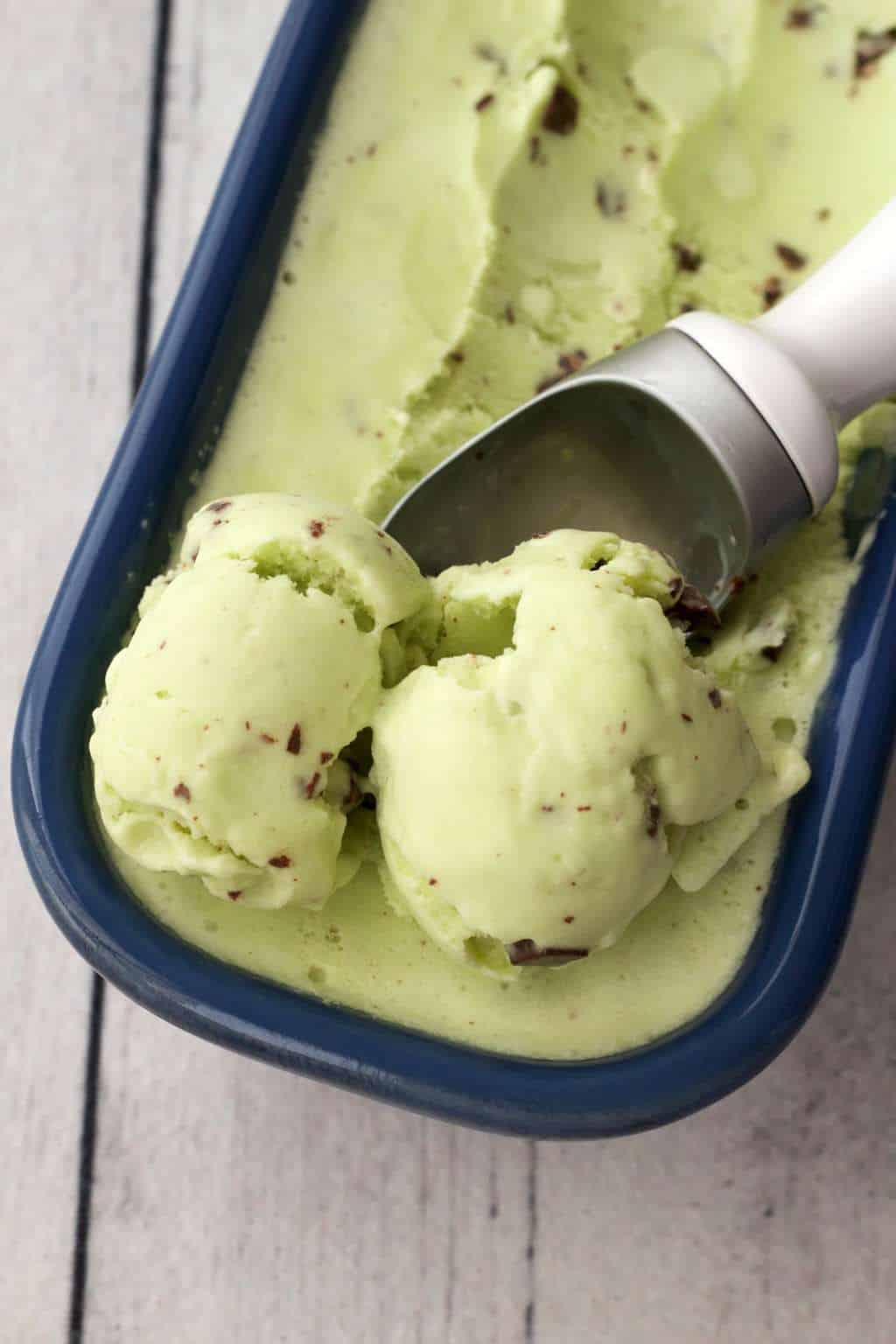 Scooping vegan mint chocolate chip ice cream with an ice cream scoop. 