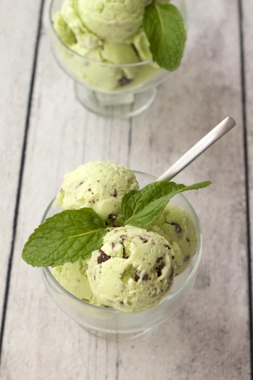 Mint chocolate chip ice cream scoops in glass bowls. 