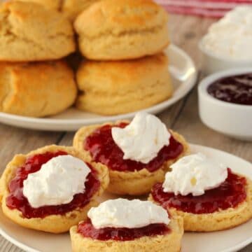 Vegan scones with jam and cream on a white plate.