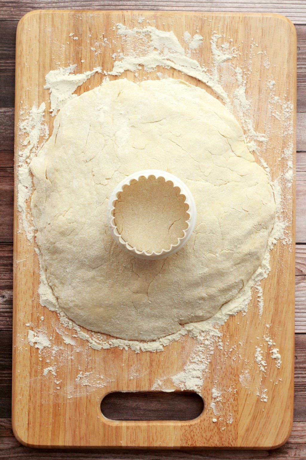Dough for vegan scones on a wooden board with a scone cutter. 