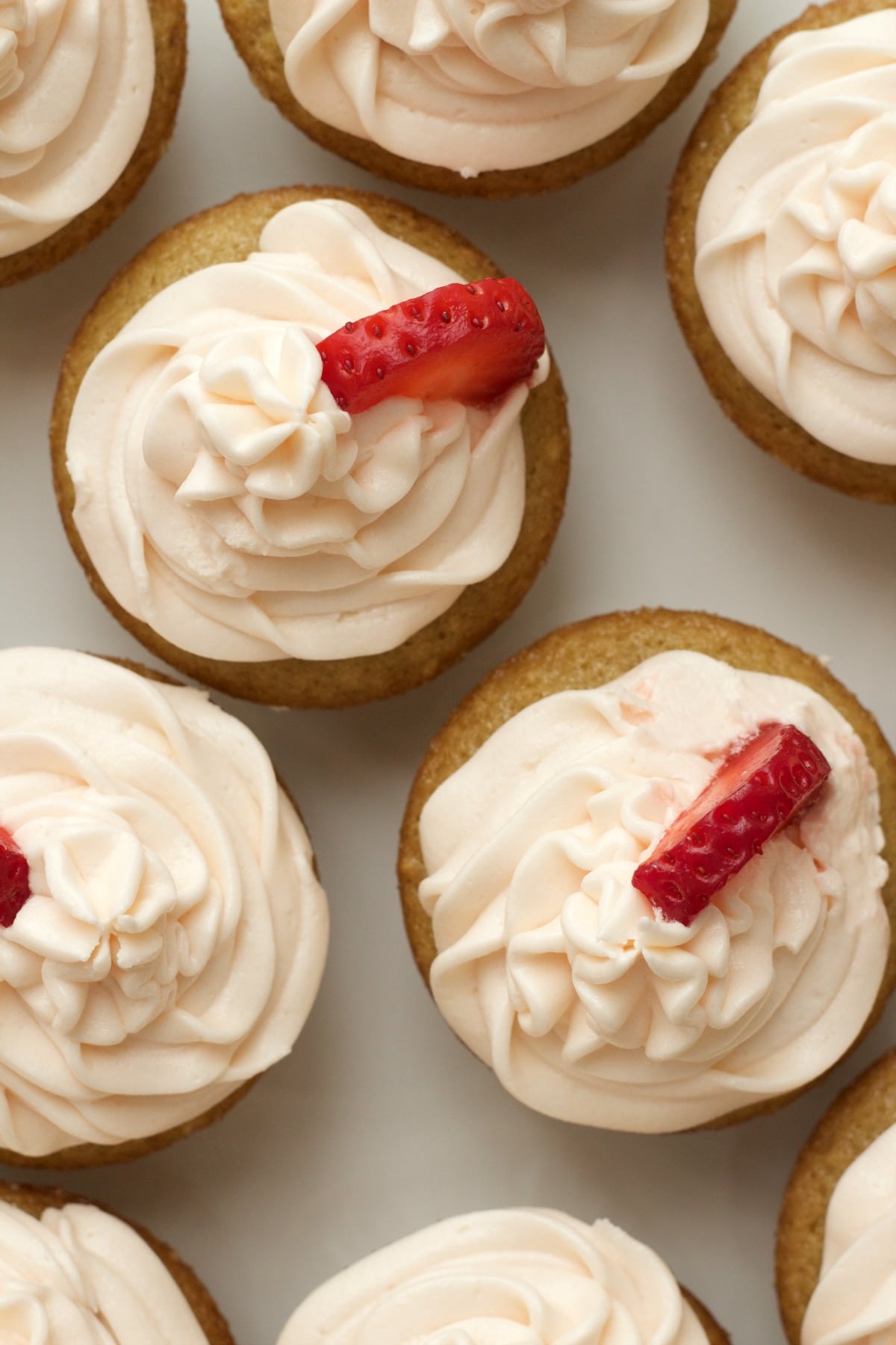 Vegan vanilla cupcakes with strawberry vanilla frosting and fresh strawberry pieces. 