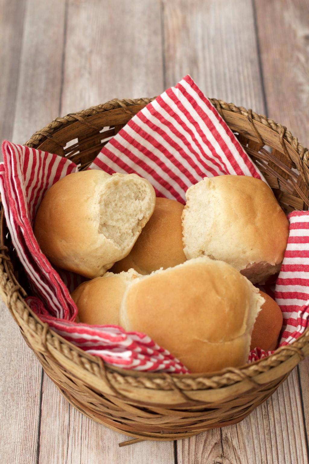 Vegan dinner rolls in a basket with a red and white striped napkin. 