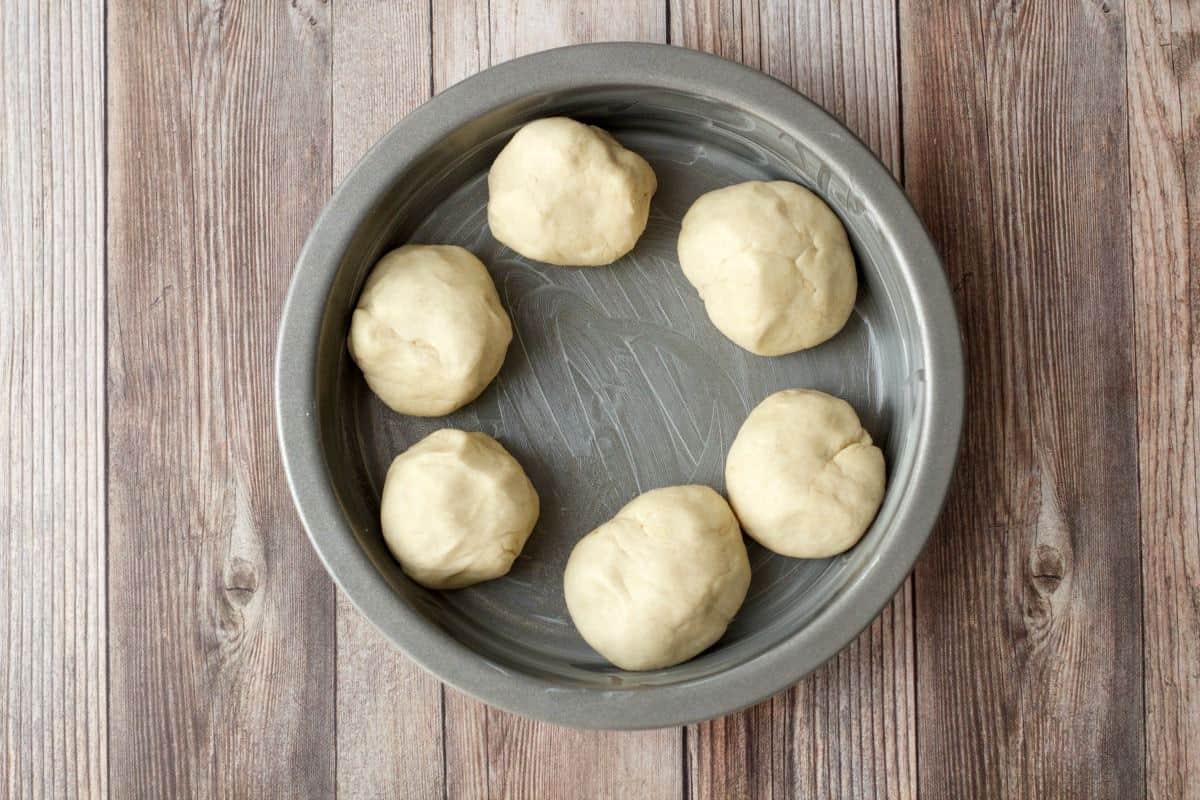 Balls of dough in a greased cake pan. 