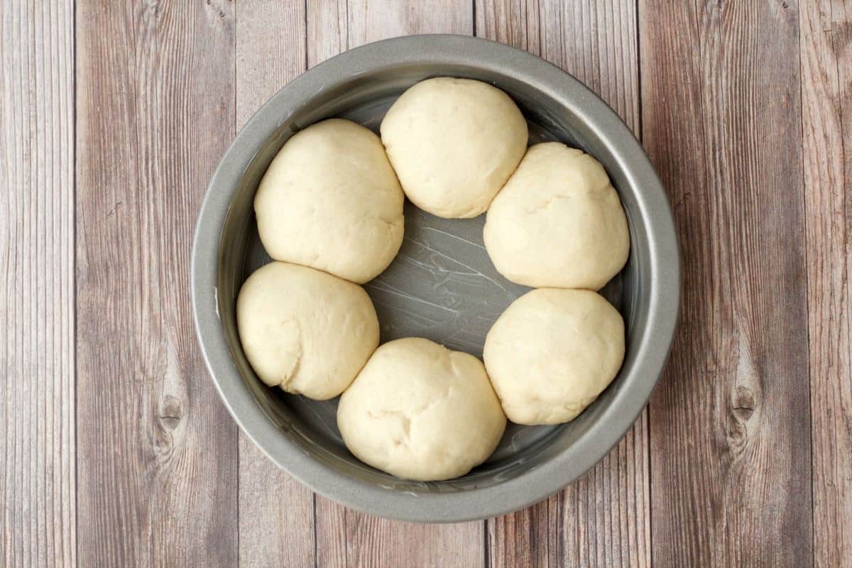 Risen balls of dough in a cake pan. 