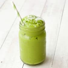 Matcha smoothie in a glass with a green and white striped straw