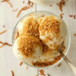Vegan coconut ice cream topped with toasted coconut in a glass bowl.