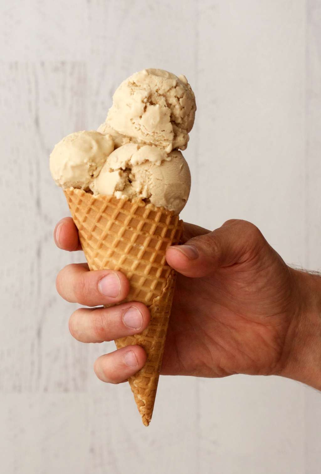 Salted caramel ice cream scoops in an ice cream cone. 