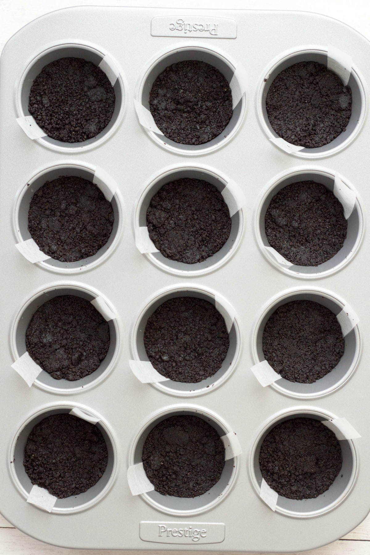 Oreo cookie crust pressed down into 12 cupcake partitions. 