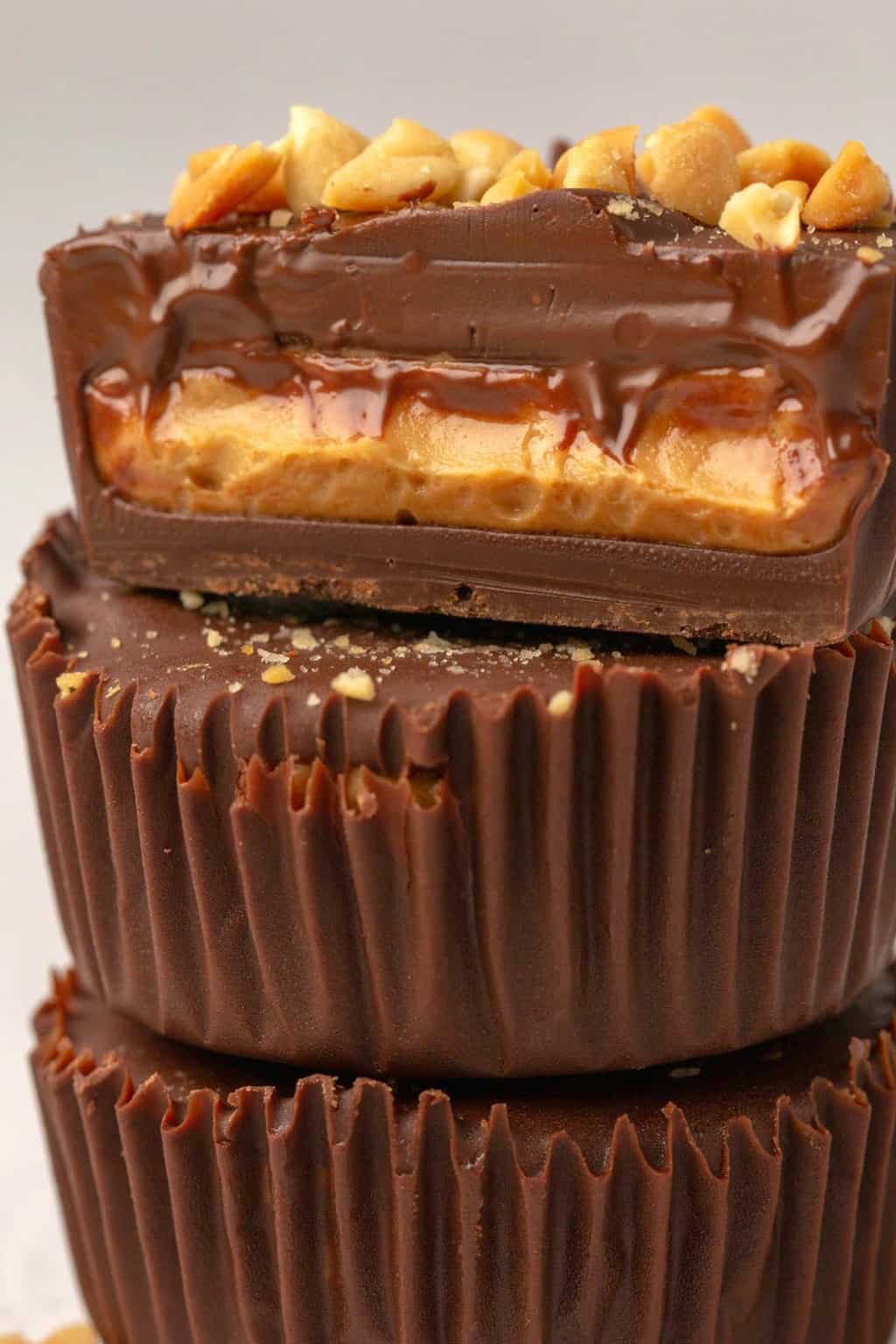 Vegan peanut butter cups in a stack with the top one cut in half to show the center. 