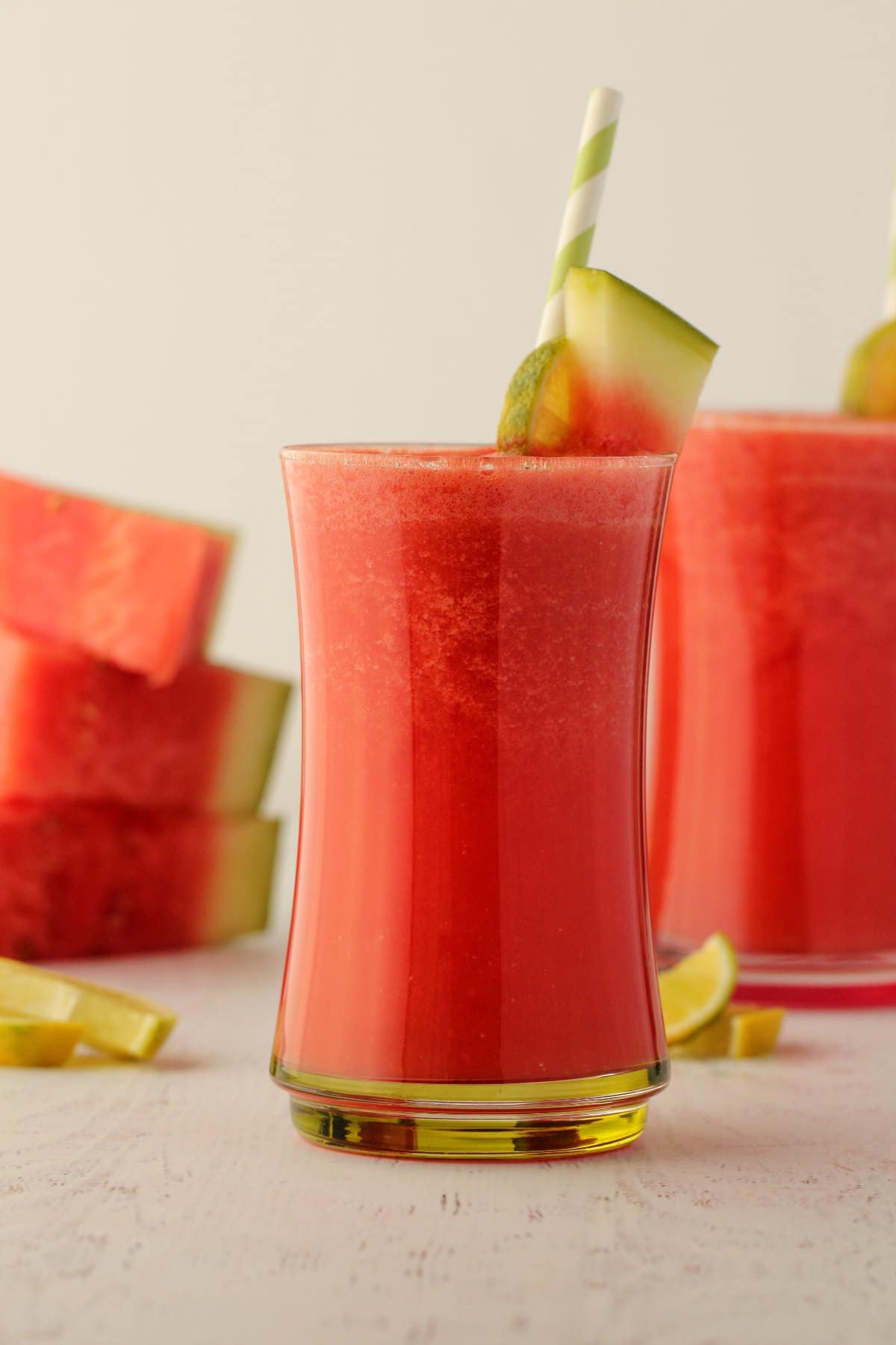 Watermelon Smoothie in a glass with a green and white straw. 