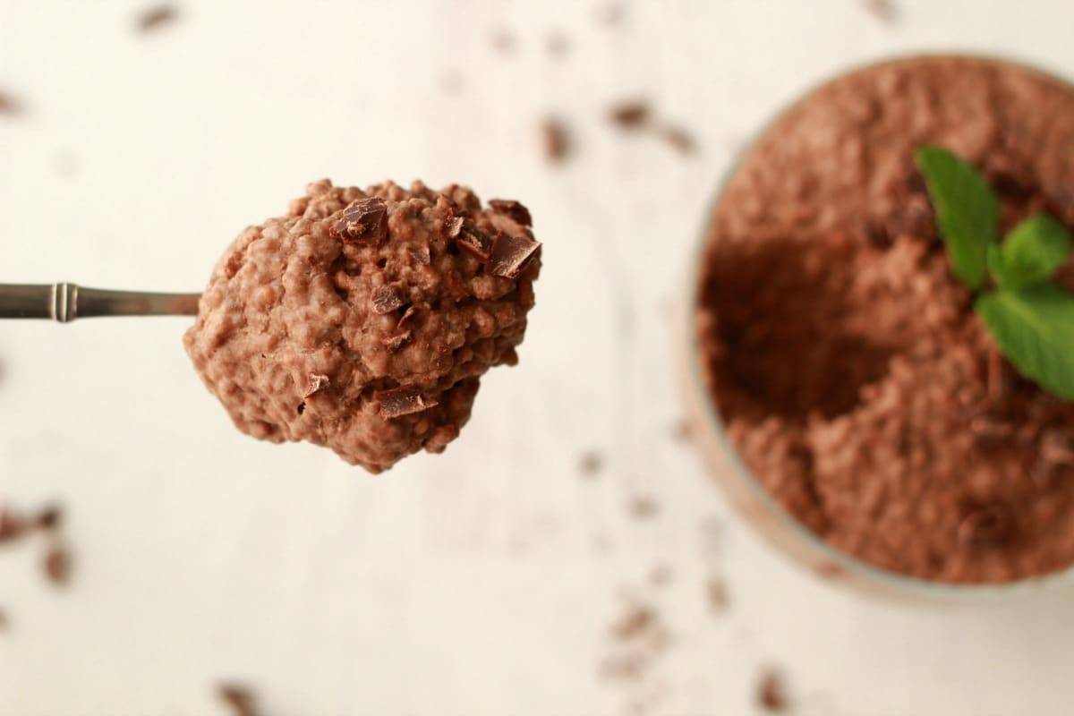Ein Löffel Schokoladen-Chia-Pudding, der sich aus einer Schale hebt. 