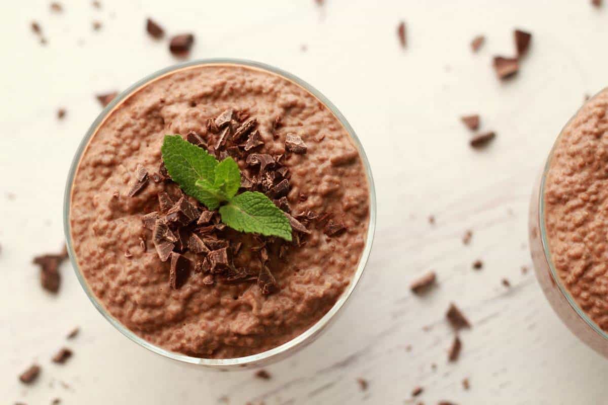 Schokoladen-Chia-Pudding in einer Glasschale mit Schokoladenstückchen und frischen Minzblättern. 