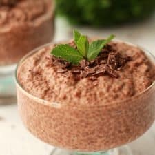 Chocolate chia pudding in glass serving dishes topped with fresh mint leaves.