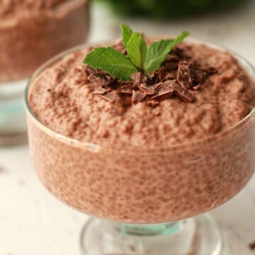 Chocolate chia pudding in a glass dish topped with vegan chocolate and fresh mint leaves.