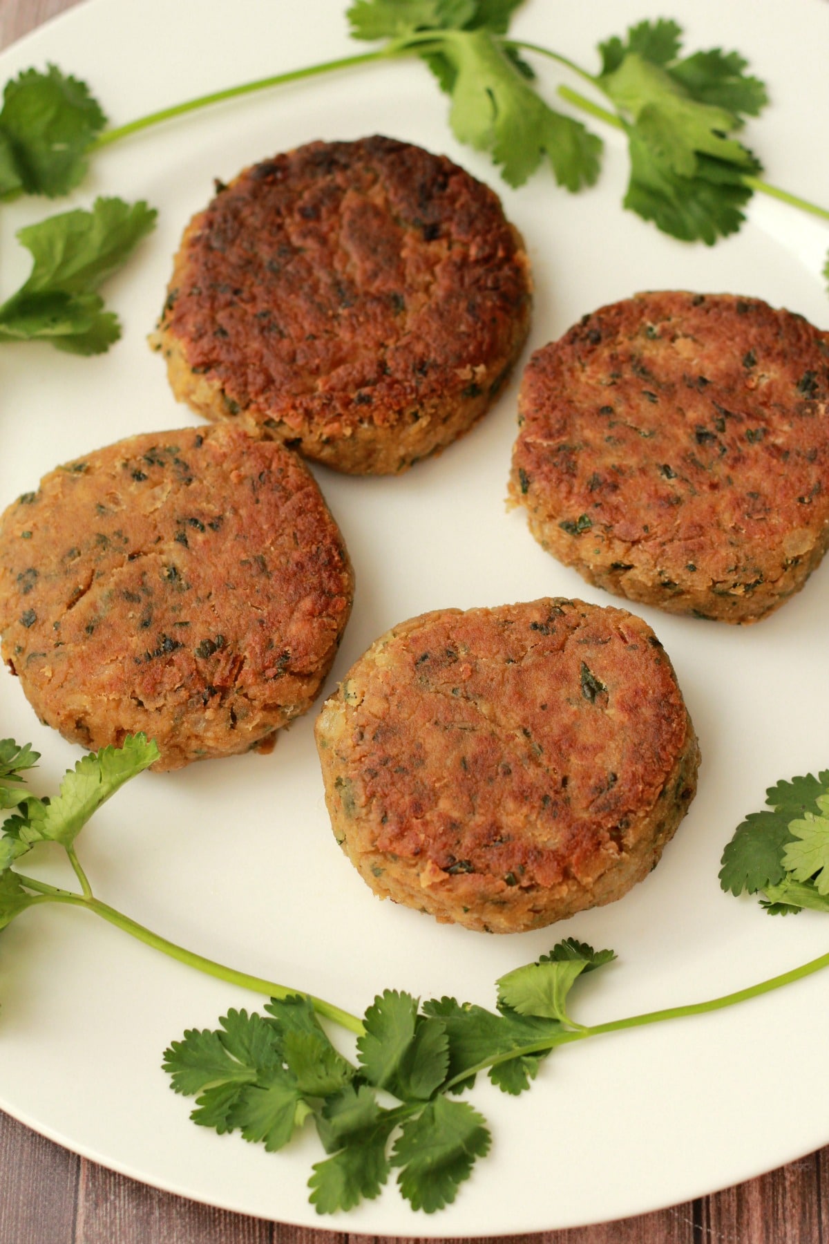 Vegan chickpea burger patties with fresh cilantro on a white plate. 