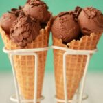 Vegan chocolate ice cream scoops in ice cream cones.