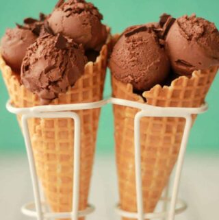 Vegan chocolate ice cream scoops in ice cream cones.