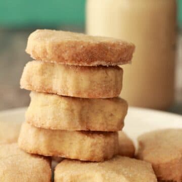 Vegan shortbread cookies stacked up on a white plate.