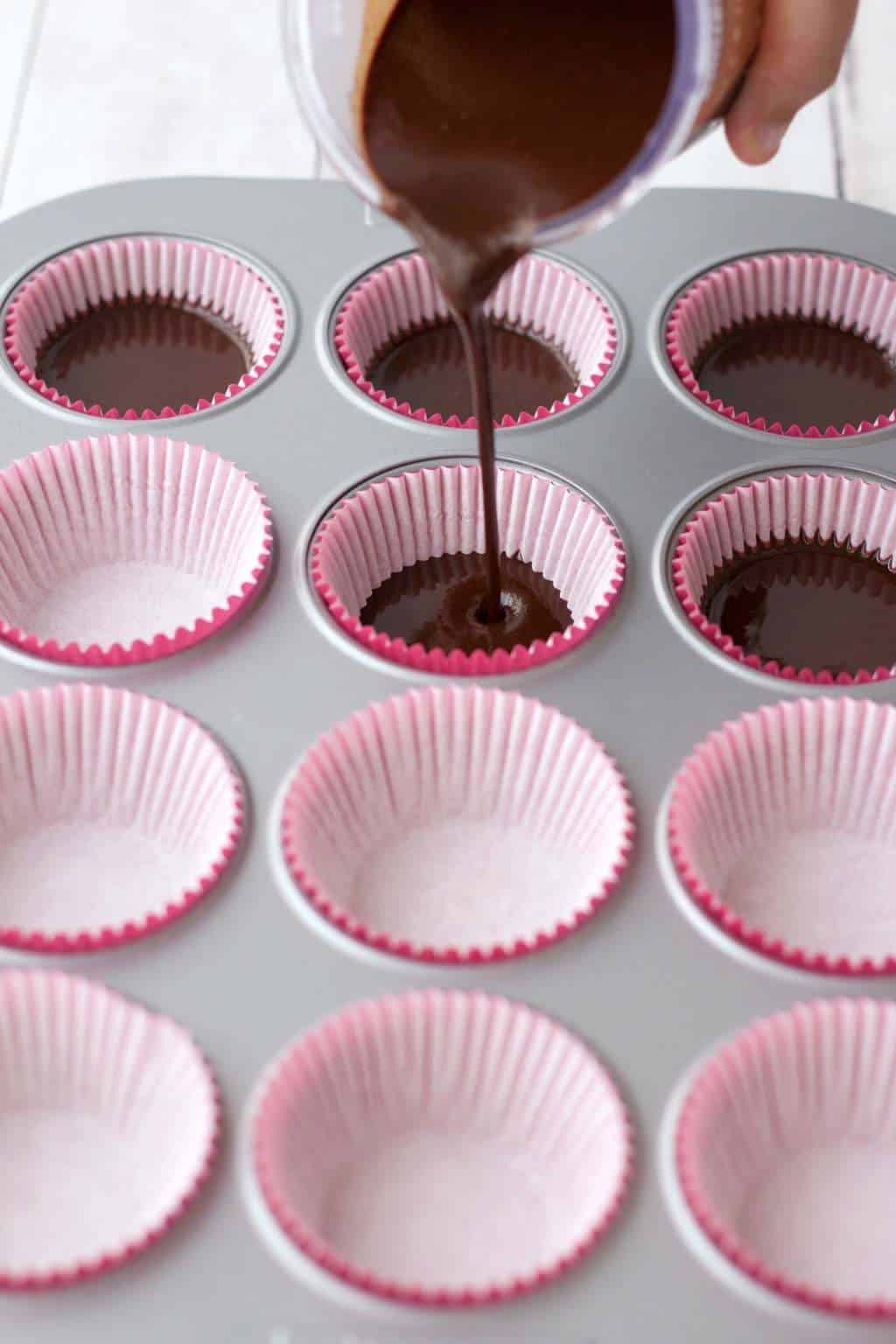 Raw chocolate pouring out into cupcake liners. 