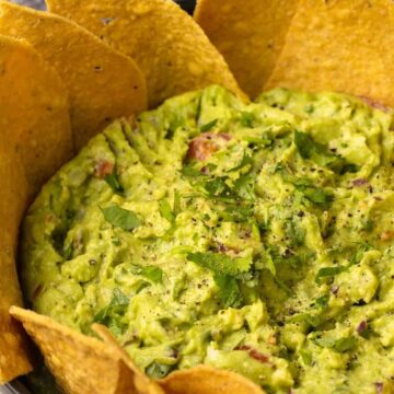 Vegan guacamole with tortilla chips in a bowl.