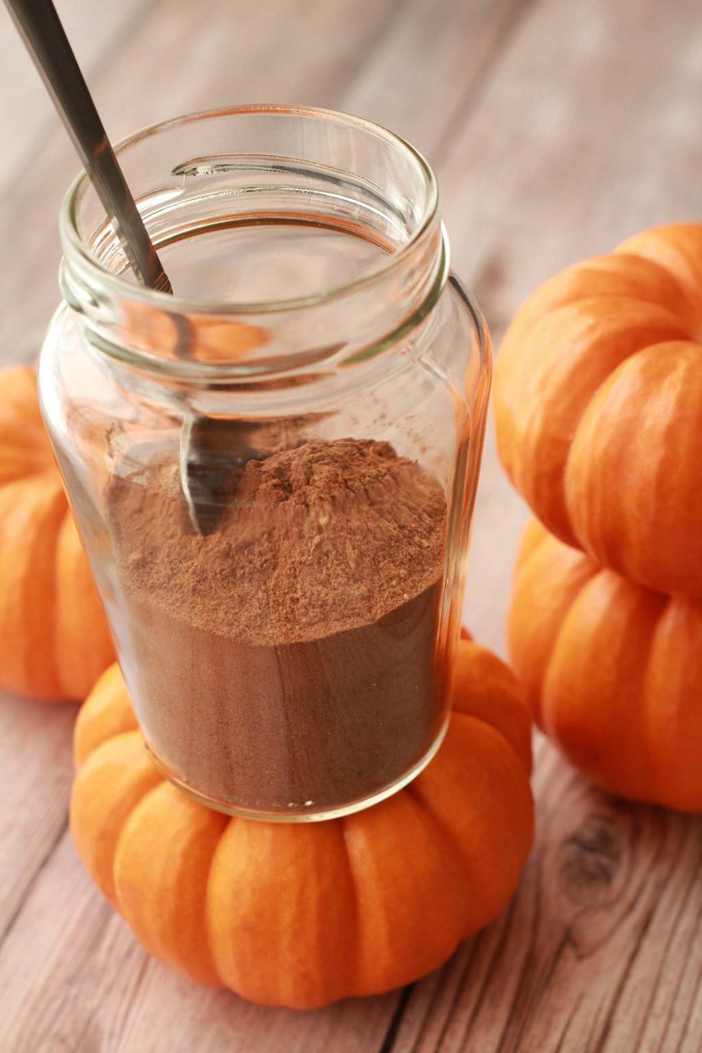 Homemade pumpkin pie spice in a glass jar with a spoon. 