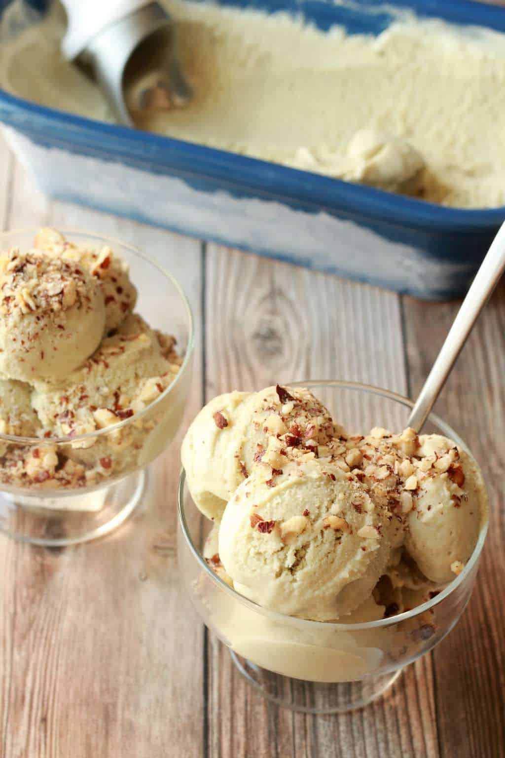 Matcha ice cream topped with chopped pecans in glass bowls. 