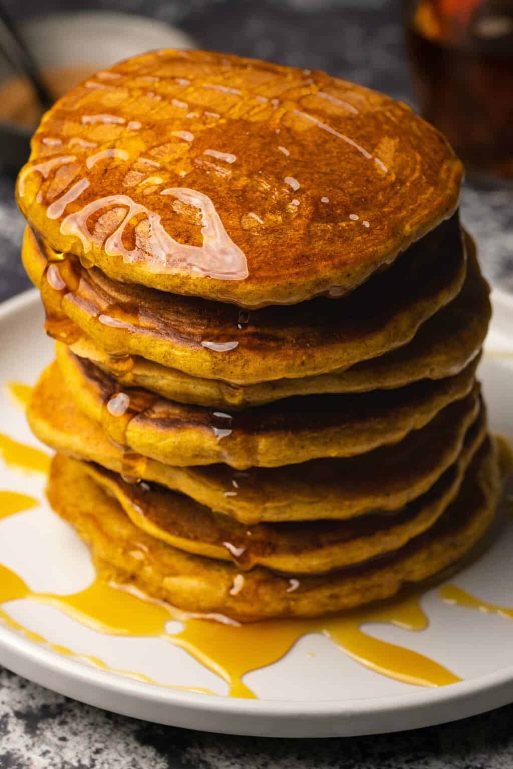 Vegan pumpkin pancakes in a stack on a white plate. 