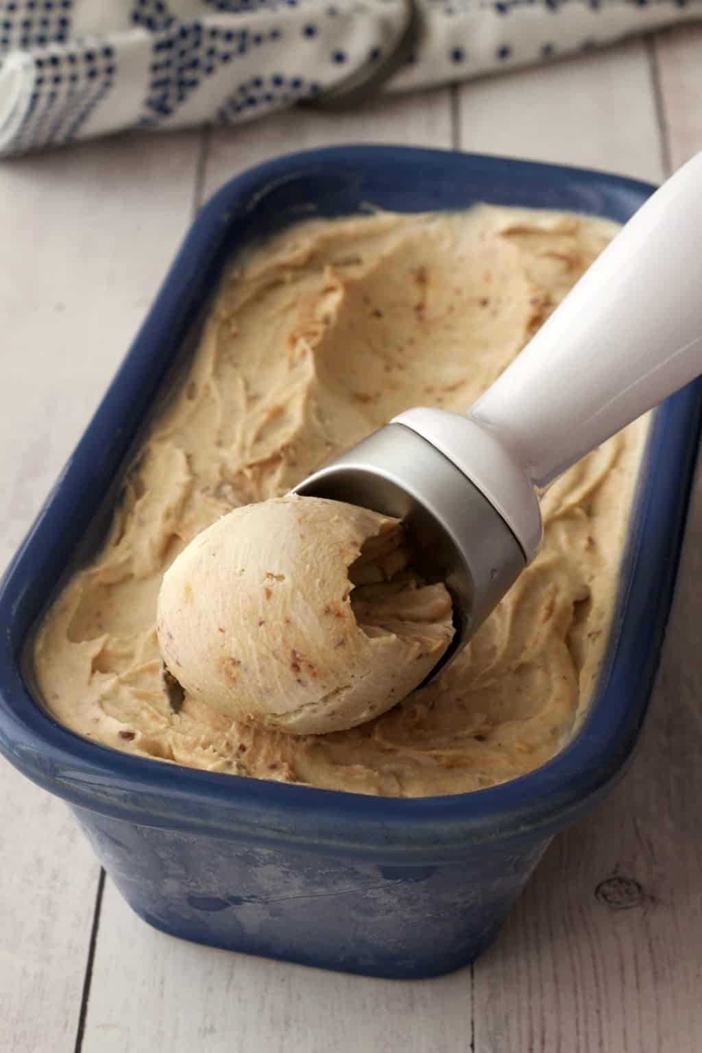 Vegan cheesecake ice cream in a blue loaf pan with an ice cream scoop. 