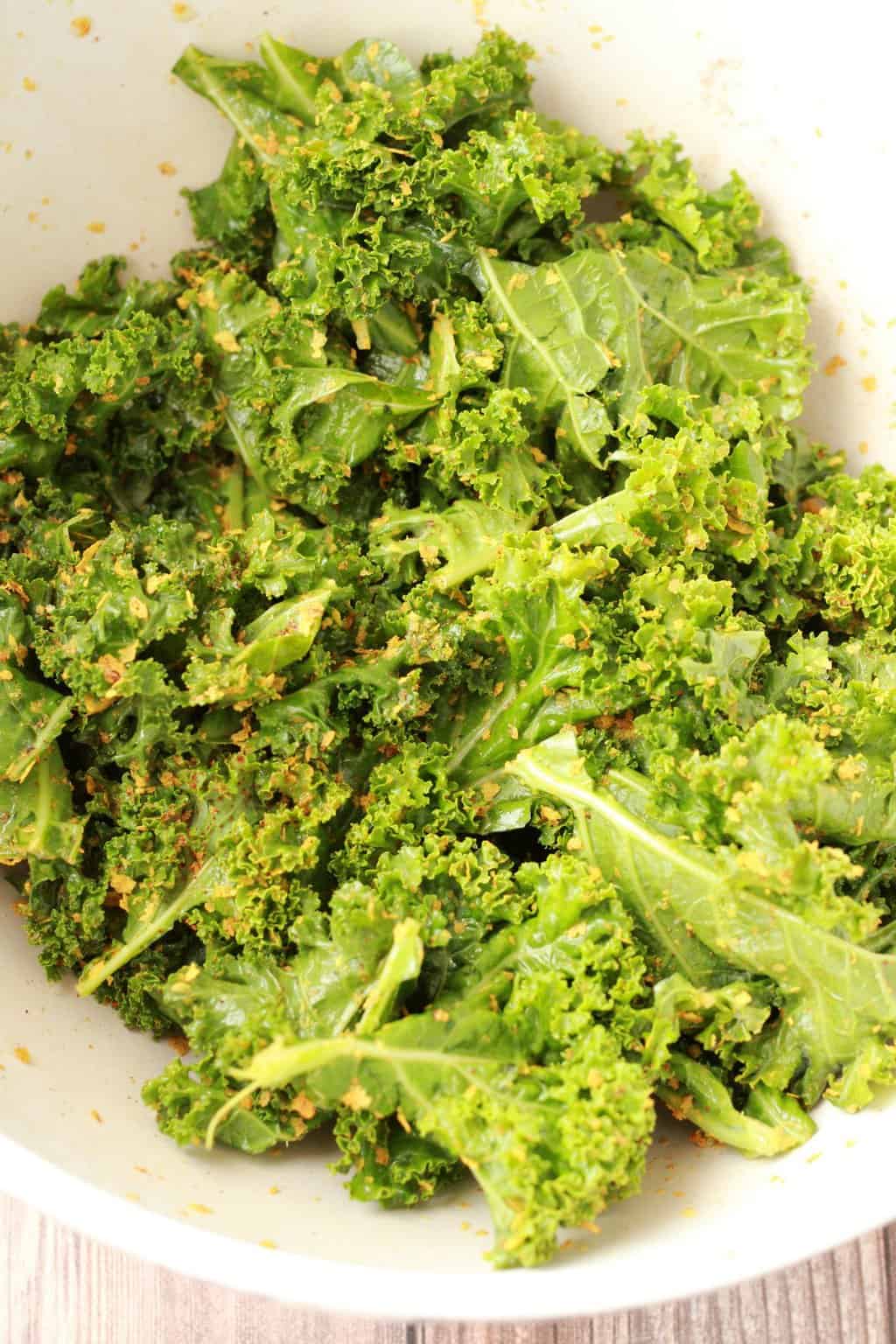 Curly kale, olive oil and spices in a bowl. 