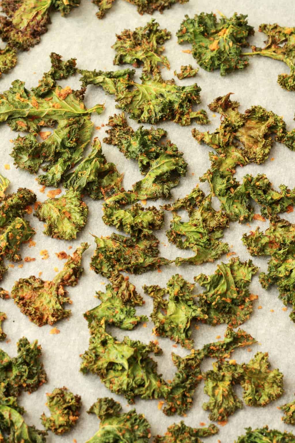Kale chips on a parchment lined baking sheet. 