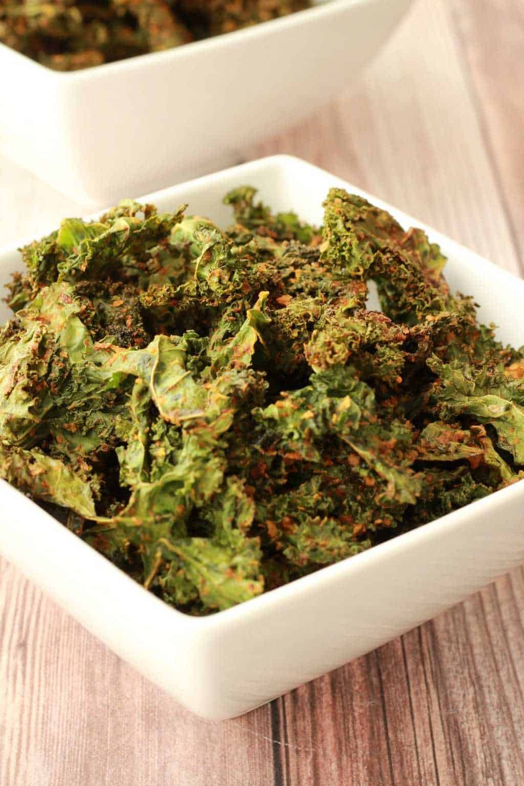 Kale chips in a square white bowl. 
