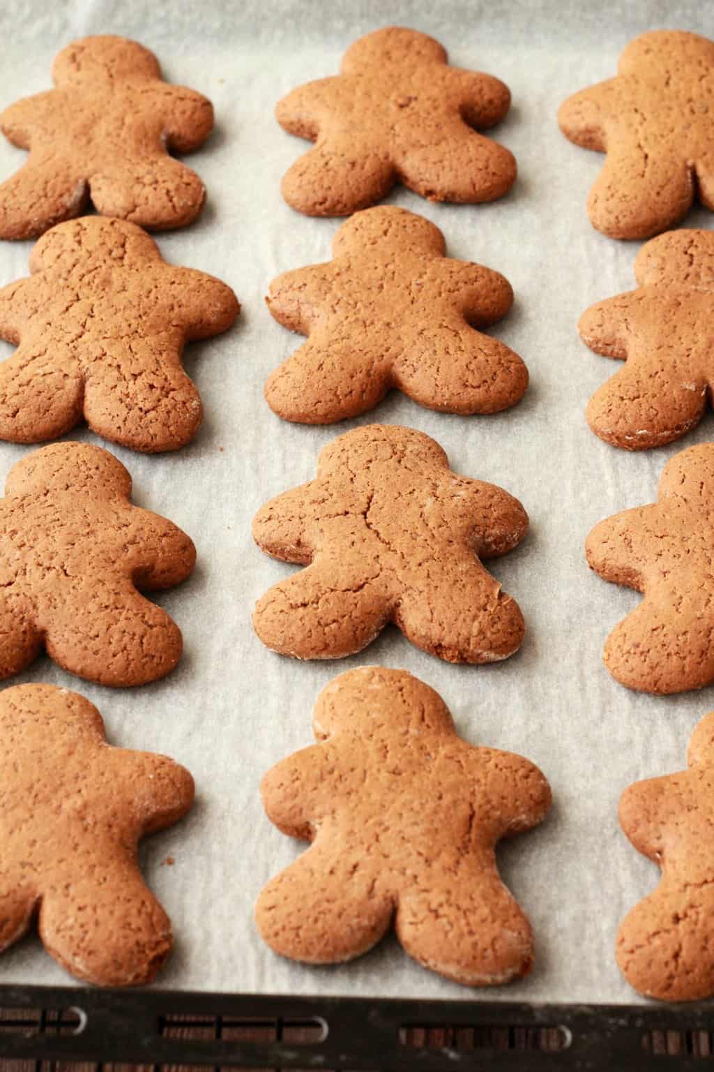 Freshly baked vegan gingerbread men on a parchment lined baking tray. 