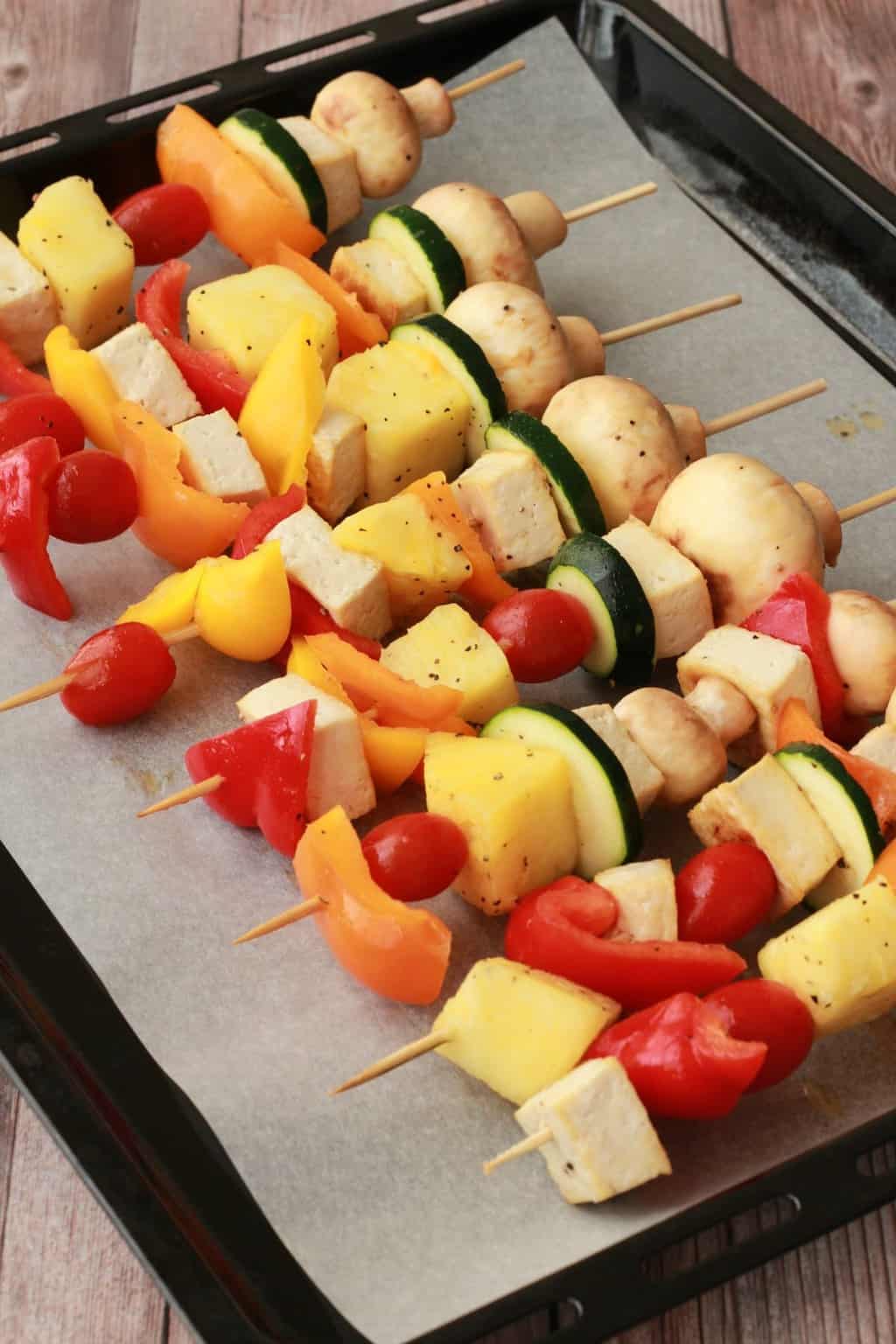 Vegetable skewers on a parchment lined baking sheet. 
