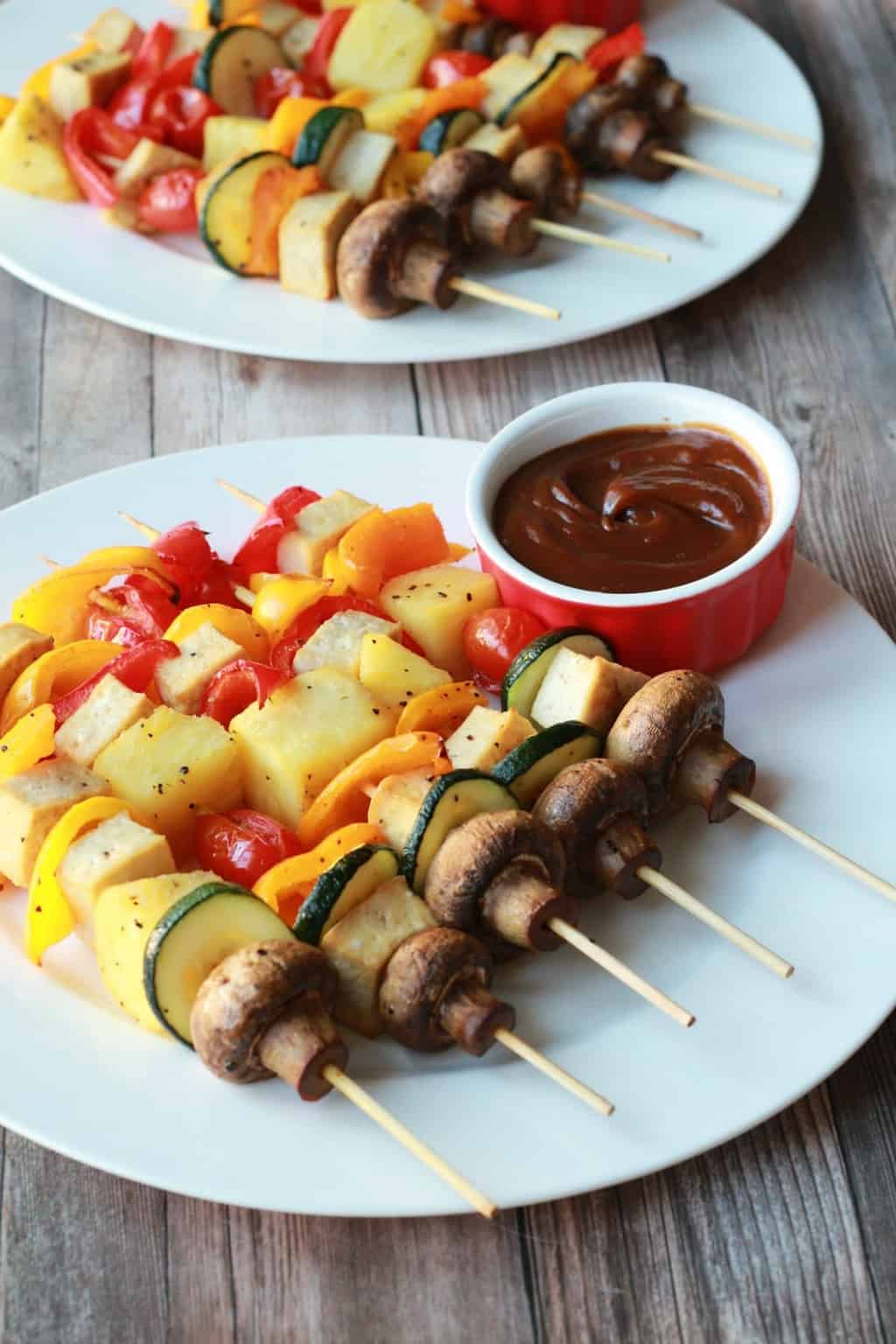 Vegetable skewers on white plates with satay sauce. 