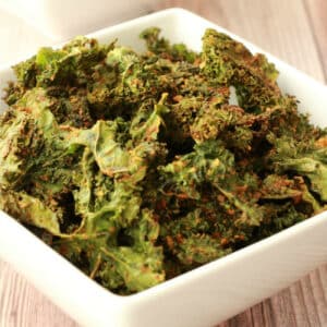 Kale chips in a square white bowl.