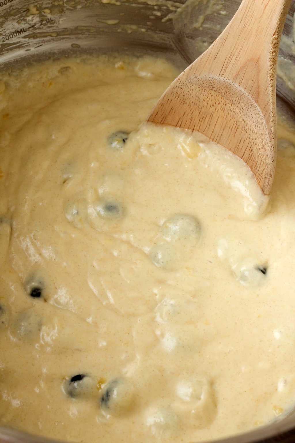 Muffin batter in a mixing bowl with a wooden spoon. 
