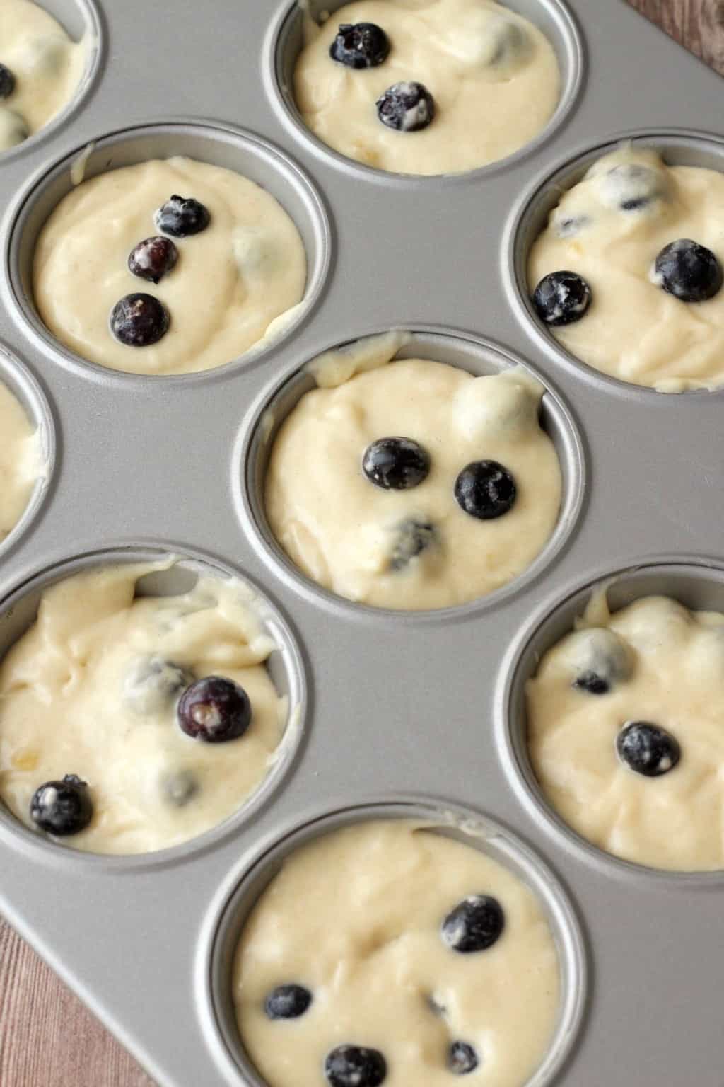 Batter for vegan blueberry muffins in a muffin tray ready to go into the oven. 