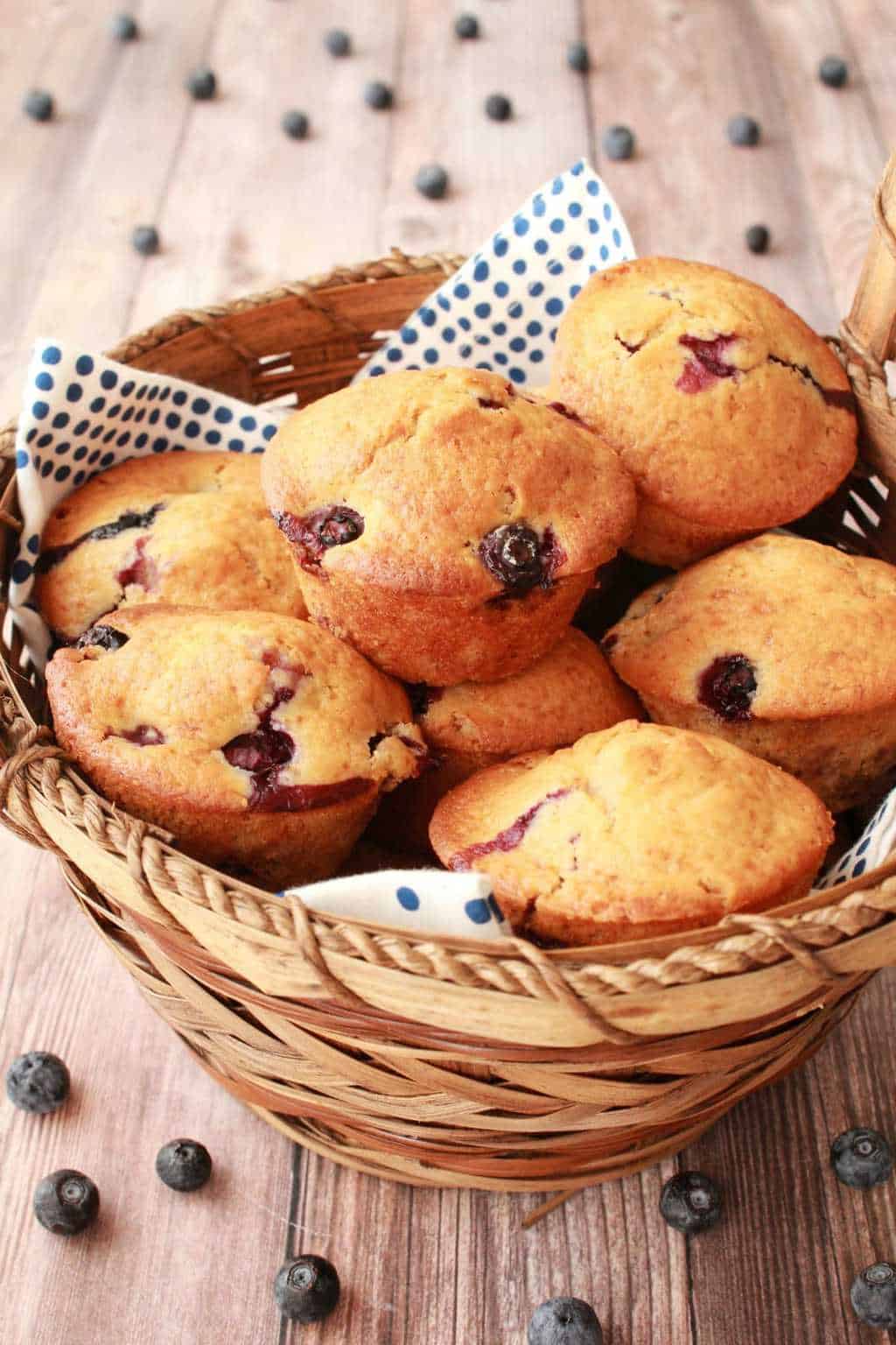 Vegan blueberry muffins in a woven basket with a blue and white napkin.