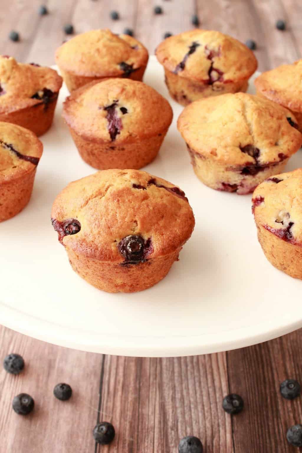 Vegan blueberry muffins on a white cake stand. 