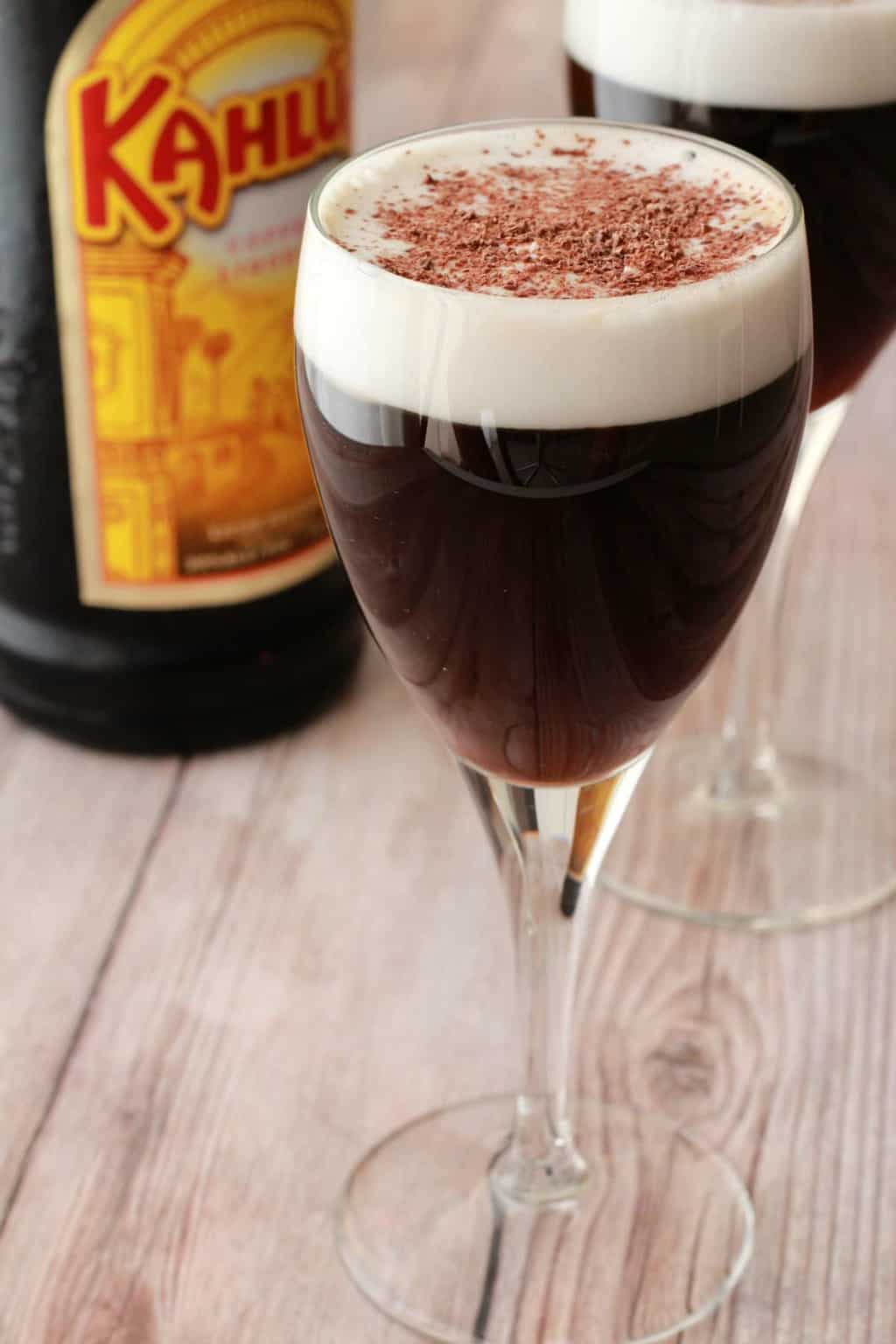 Kahlua coffee in wine glasses topped with vegan whipped cream and chocolate shavings. 